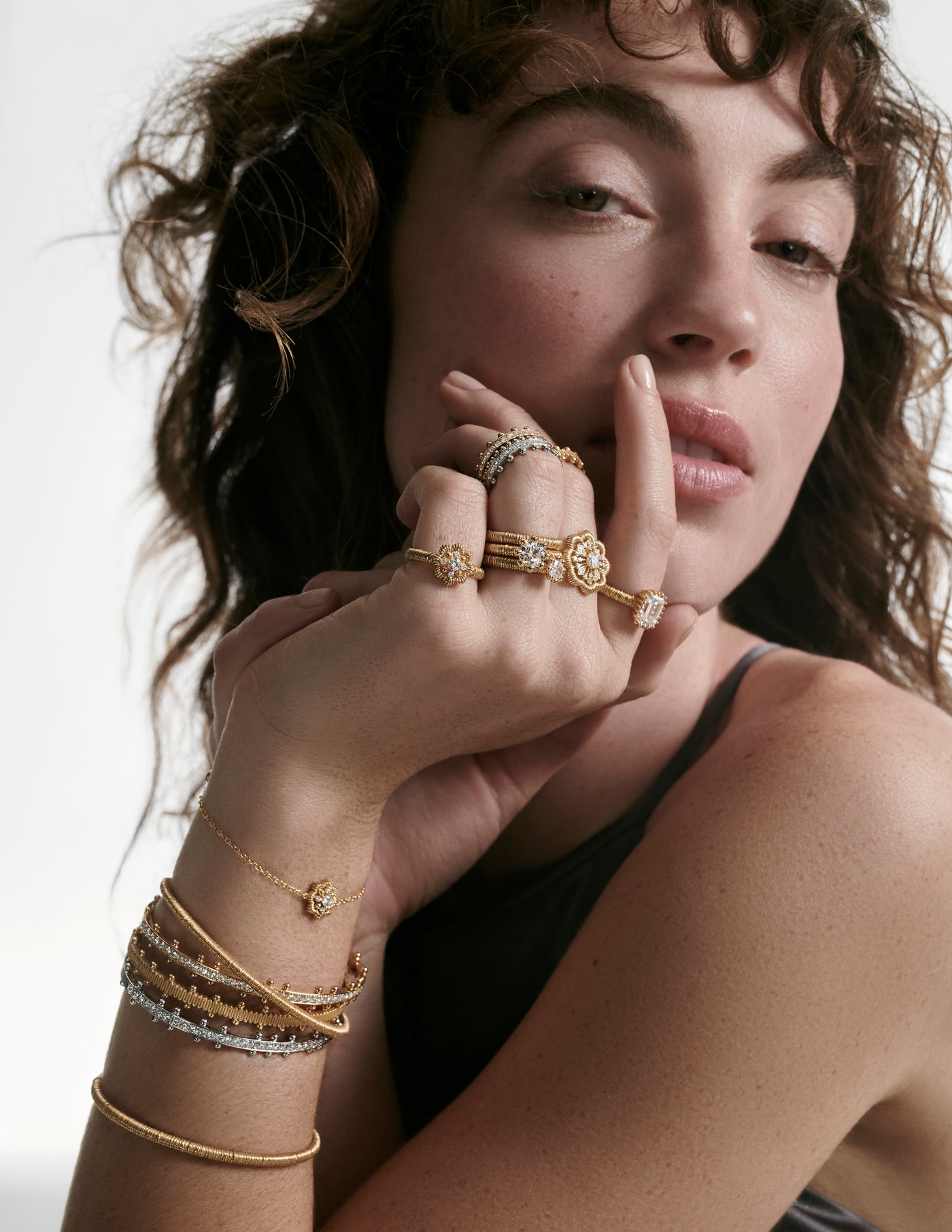 A woman wearing the entire ring and bracelet collection from Oscar Massin