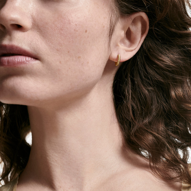 Woman wearing filigree earrings made of 18K recycled yellow gold by Oscar Massin