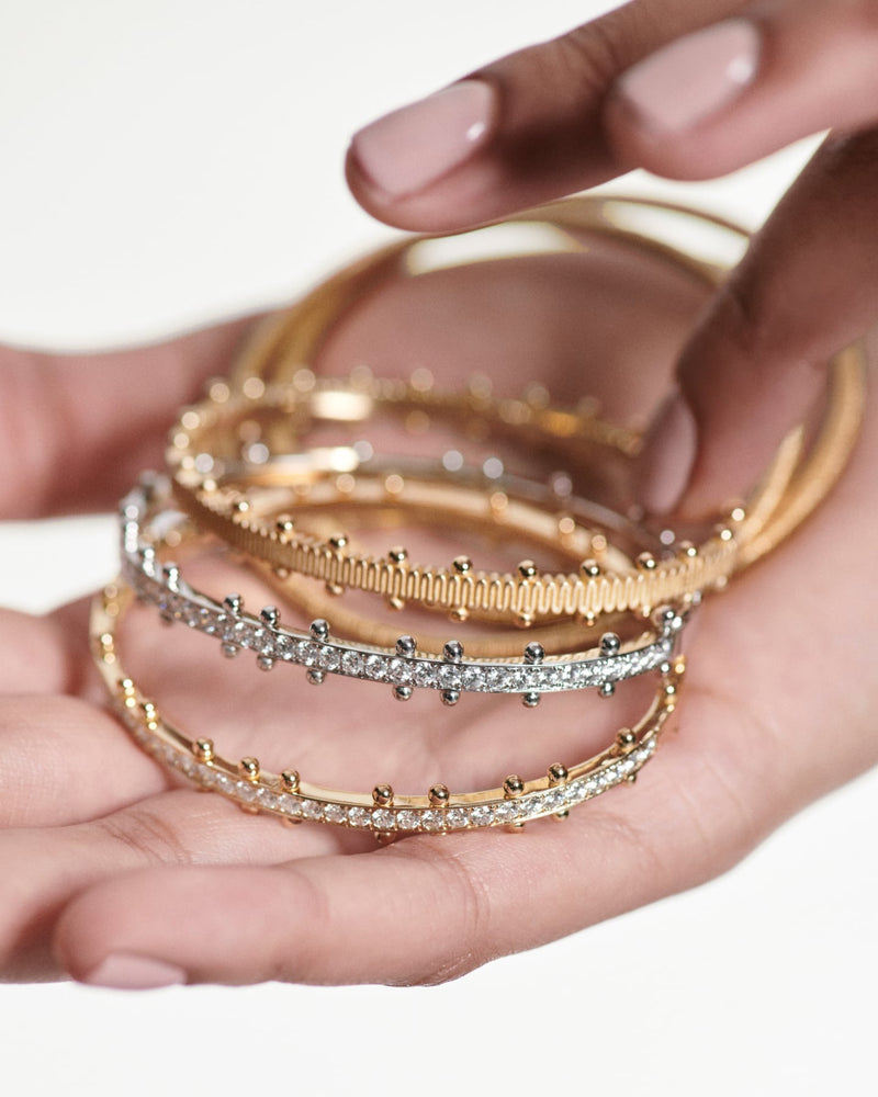 hand holds 3 stacked beaded bracelets of lab grown diamonds & 18k recycled yellow & white gold for oscar massin jewelry