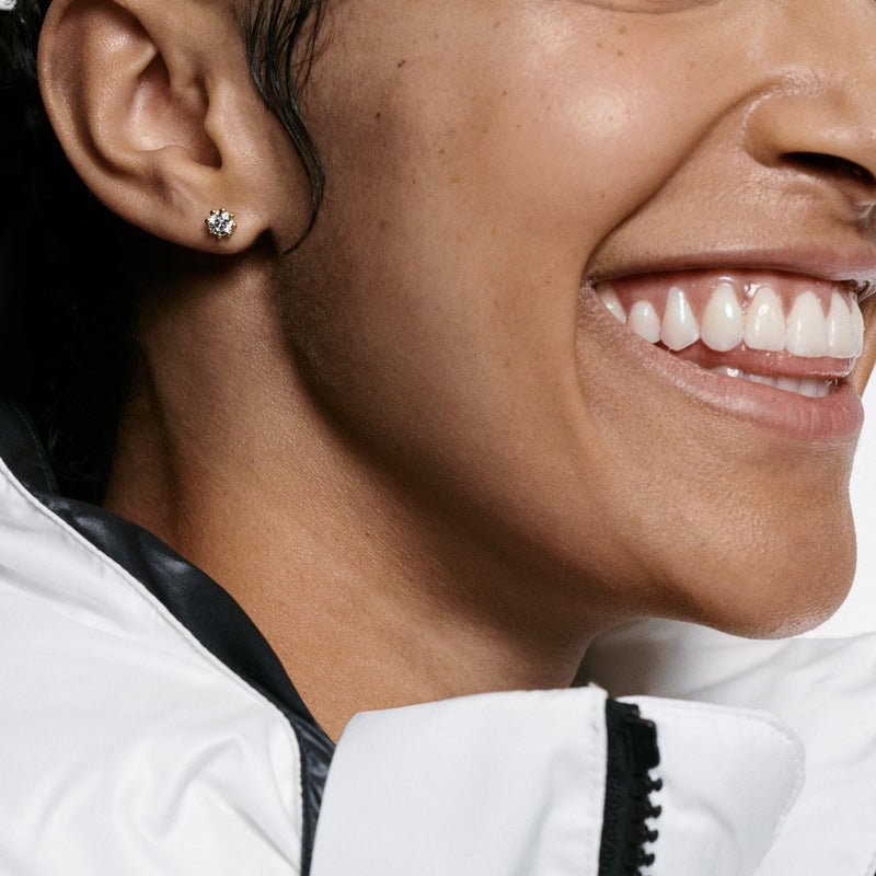 Woman wears Oscar Massin fine jewelry small stud earrings made of recycled yellow gold with sustainable lab grown diamonds