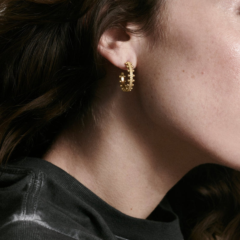 Woman wearing beaded hoop earrings in recycled yellow gold by Oscar Massin